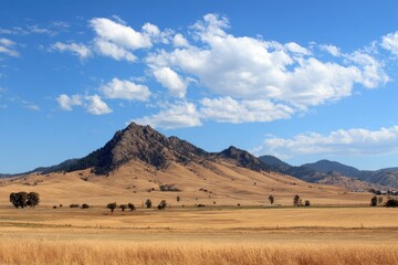 Obraz premium Dry, rolling plains meet a rocky mountain peak under a blue sky