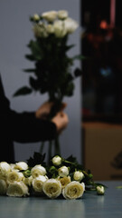 Beautiful white roses in a flower shop. Florist assembles a bouquet to order