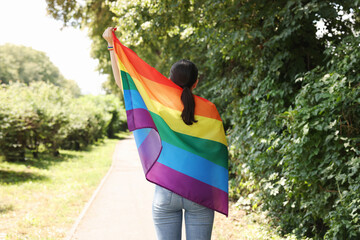 LGBT concept. Woman with rainbow flag outdoors, back view