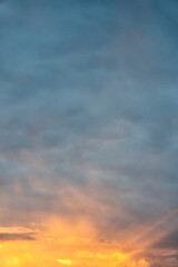 Mesmerizing natural light show in evening sky as sun descends, painting clouds in vibrant hues of orange, yellow, and deep blue
