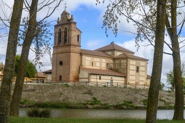Fototapeta premium Church of San Pelayo in Villarrabe, Palencia, beside the river under cloudy sky