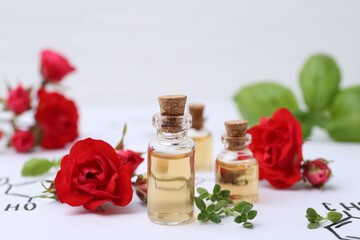 Bottles of cosmetic products, herbs and red roses on paper with chemical formulas, closeup