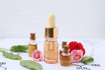 Bottles of cosmetic products, herbs and roses on paper with chemical formulas, closeup