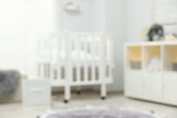 Baby room interior with stylish crib and other furniture, blurred view