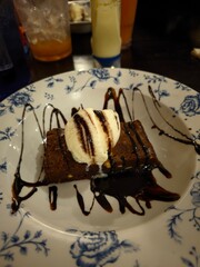 Delicious brownie with vanilla ice cream and chocolate sauce on a floral plate, dessert