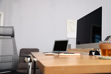 Stylish workplace with modern computer, other devices and stationery on wooden desk indoors