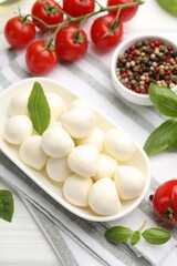 Tasty mozzarella cheese, tomatoes, basil and spices on white wooden table, above view