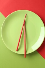 Stylish plate and chopsticks on color background, top view