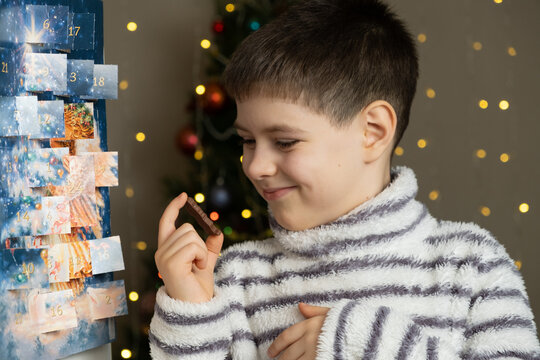 A little boy holding a chocolate Santa figurine from the advent calendar in his hands