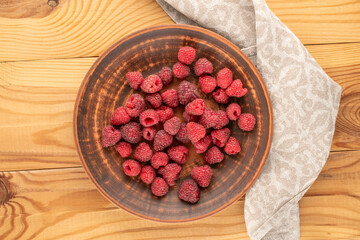 Sweet ripe raspberries on a wooden table, close-up, top view.