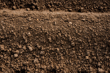 Close-up view of freshly tilled brown soil with rich texture and small clumps, ready for planting crops in an agricultural field.
