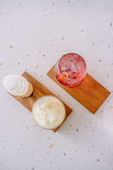 Refreshing strawberry squash and iced coffee latte on a rustic wooden coaster, perfect for a hot day. A delightful and vibrant beverage duo