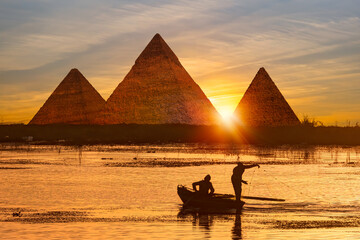 Giza pyramid Complex by the Nile at amazing sunset - Fishermen casting their fishing nets on a boat in Nile river at amazing sunset - Egypt