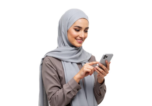 A cheerful Muslim woman wearing a grey hijab happily using a smartphone, isolated on a white studio background.