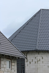 New metal tile roofs on modern buildings under construction, cloudy day, close-up view, architecture and real estate development concept