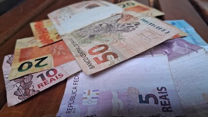 Brazilian real notes superimposed on a wooden background