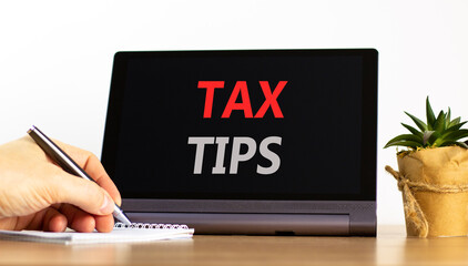 Tax tips symbol. Concept word Tax tips on beautiful black tablet. Businessman's hand with pen. Calculator. Beautiful white background. Business tax tips concept. Copy space.