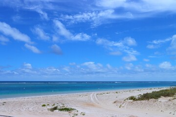 Sandy beach facing Indian Ocean with blue sky and clouds