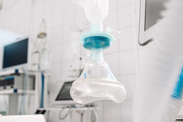 Medical anesthesia mask suspended in a sterile surgical environment, showcasing advanced healthcare technology and equipment, emphasizing patient care and safety during surgical procedures