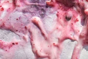 Fototapeta premium close up of swirled berry yogurt with pink and purple fruit streaks on a white background.