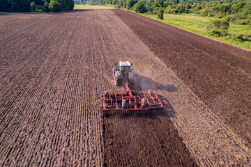 tractor cultivating a field with a harrow
