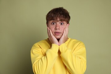 Teenage boy suffering from panic attack on green background