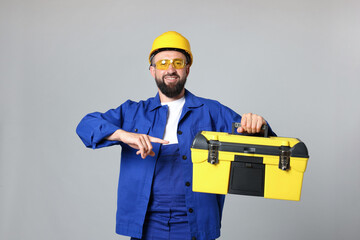 Professional repairman with tool box on grey background