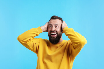 Handsome man laughing on light blue background