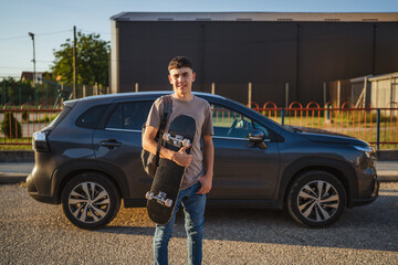Young student holding skateboard next to car in parking lot © Miljan Živković