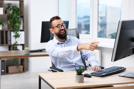 Man in glasses laughing at table in office