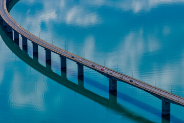 Aerial view of Lake Polyfytos in Greece with a curved bridge,