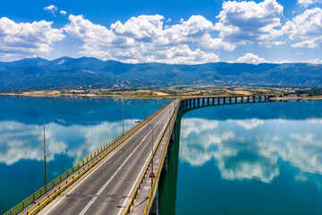 Obraz premium Aerial view of Lake Polyfytos in Greece with a curved bridge,
