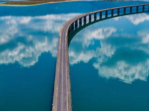Aerial view of Lake Polyfytos in Greece with a curved bridge,