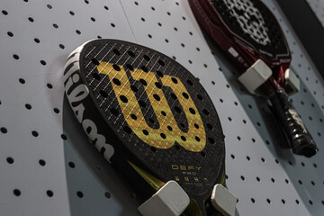 A variety of padel rackets are displayed in a sports shop.