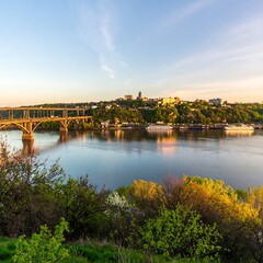 Naklejka premium Panoramic View of Cityscape with Bridge over Tranquil River at Sunset, Ukraine