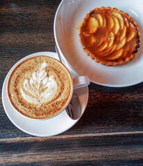 A cup of cappuccino with cinnamon and an apple tartlet
