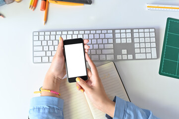 Mockup smartphone on woman hands using on office workspace.