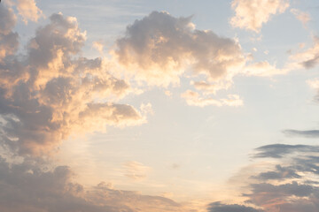 Obraz premium Colorful clouds in the blue sky illuminated by the warm light of the setting sun.