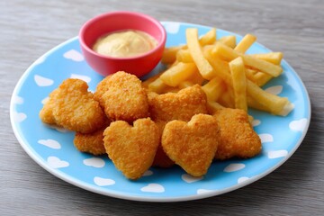 Heart shaped chicken nuggets with french fries and honey mustard dipping sauce on blue plate