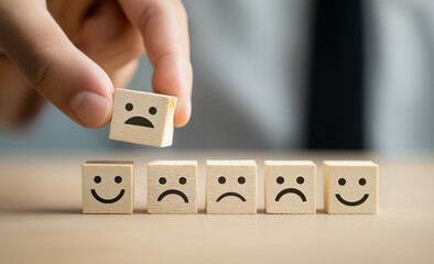 a girl Hand placing a smiley face symbol on a wooden block, with happy, sad, and neutral face symbols, against a blue background,