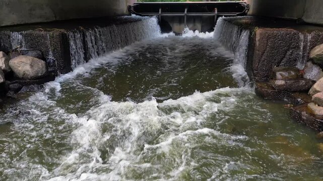 small dam fish ladder running water fall under bridge from drone