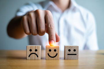 Customer Feedback Concept with Hand Selecting Happy Face on Wooden Block for Satisfaction