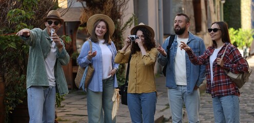 Naklejka premium Guide with microphone and group of tourists on city street during excursion