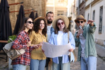 Guide with microphone and group of tourists on city street during excursion