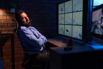 Tired security guard monitoring CCTV cameras in office at night