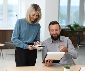 Fototapeta premium Smiling business partners working with documents at table in office