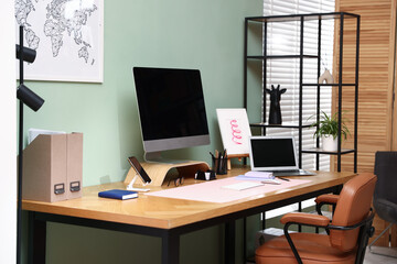 Stylish workplace with modern computer, other devices and stationery on wooden desk indoors