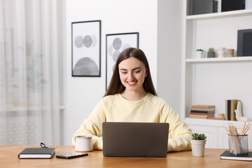 Copywriter using laptop at wooden table indoors