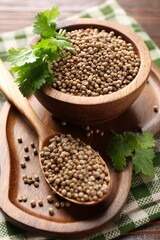 Coriander seeds and fresh cilantro sprigs on wooden table, closeup