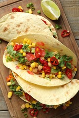 Tasty vegetarian tacos with chickpeas, corn and quinoa served on wooden table, top view